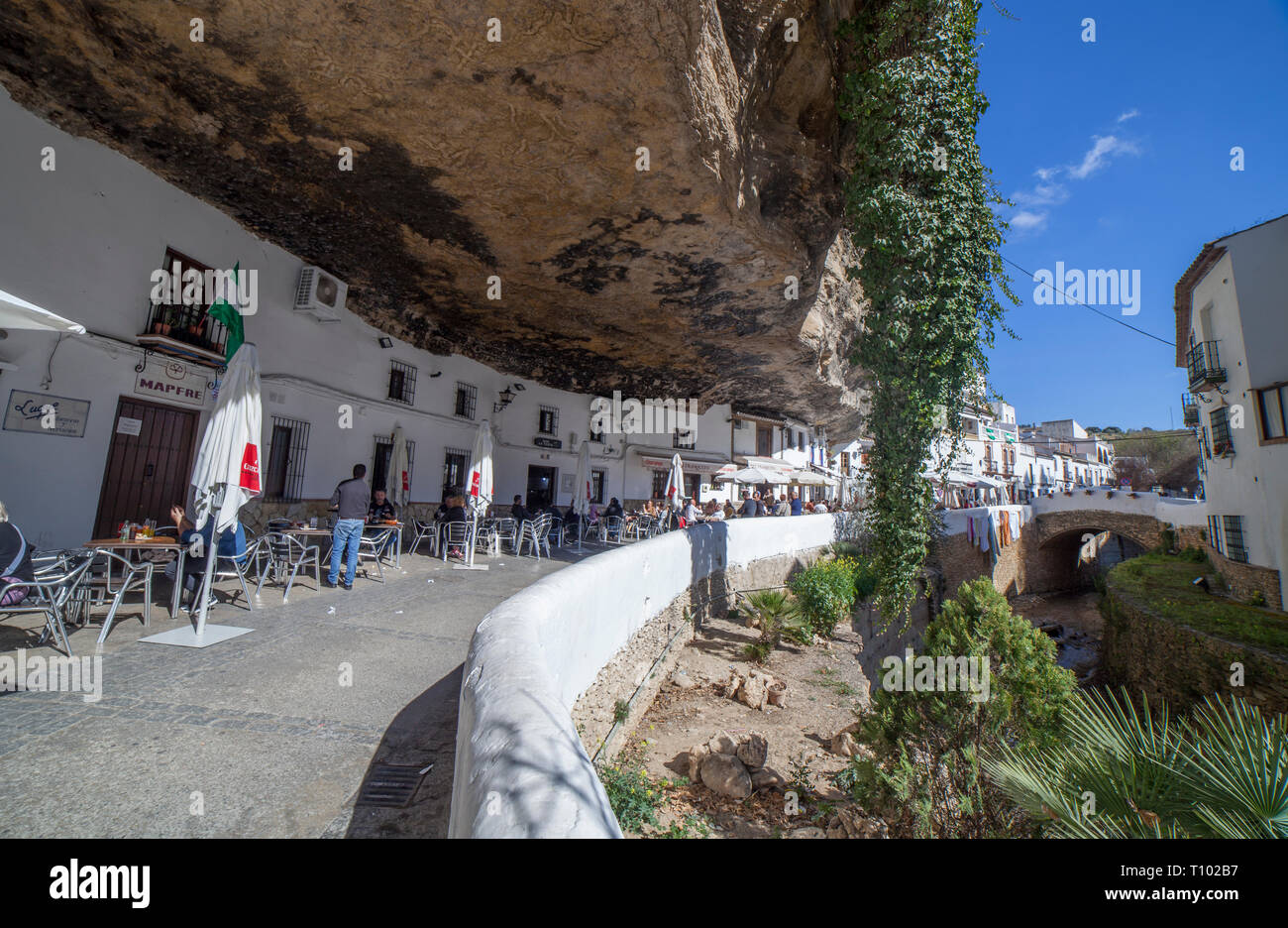 Setenil, Spanien - 4. März, 2019: Straße mit Wohnungen in Felsen Überhänge gebaut. Setenil de las Bodegas, Cadiz, Andalusien, Spanien. Restaurant des sonnigen Höhlen Stockfoto