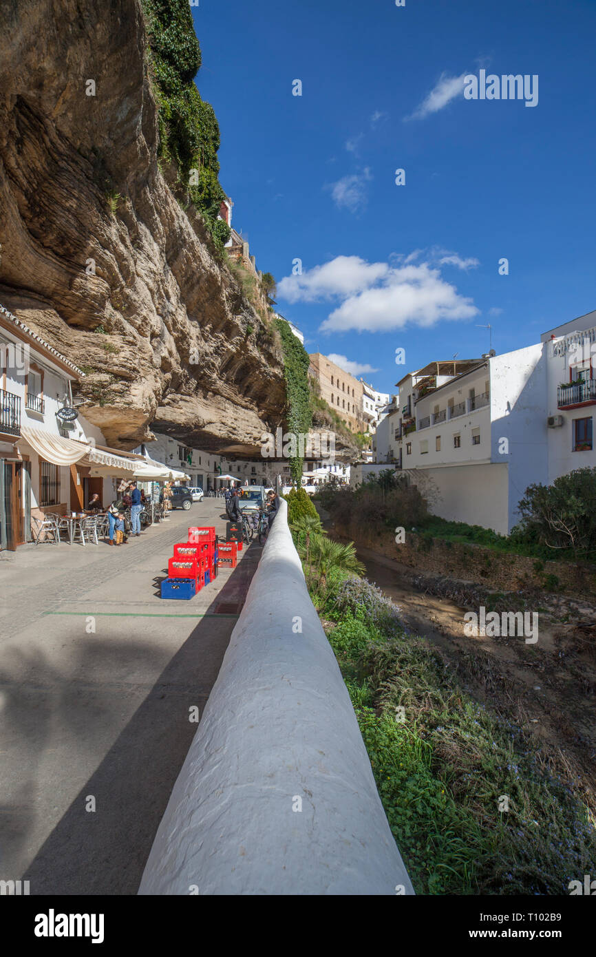 Setenil, Spanien - 4. März, 2019: Straße mit Wohnungen in Felsen Überhänge gebaut. Setenil de las Bodegas, Cadiz, Andalusien, Spanien. Restaurant des sonnigen Höhlen Stockfoto