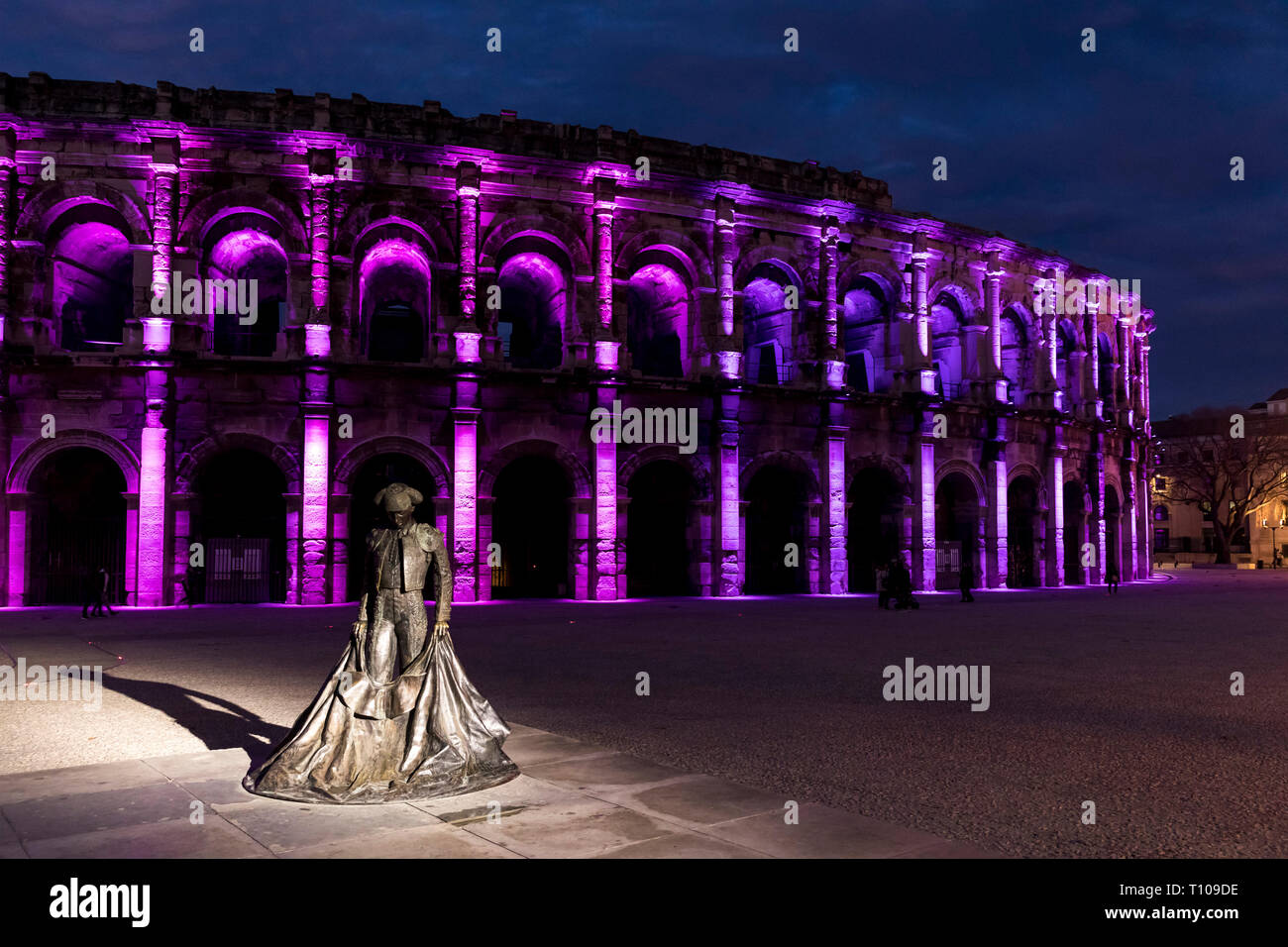 Nimes (Frankreich): die Arena bei Einbruch der Dunkelheit mit einer Statue der Christlichen Montcouquiol ('Nimeno II") und Weihnachtsbeleuchtung Stockfoto
