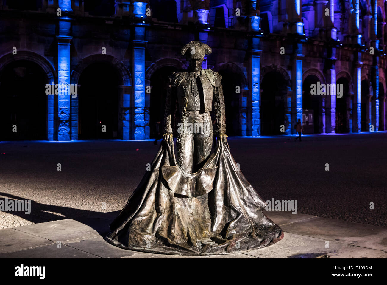 Nimes (Frankreich): die Arena bei Einbruch der Dunkelheit mit einer Statue der Christlichen Montcouquiol ('Nimeno II") und Weihnachtsbeleuchtung Stockfoto
