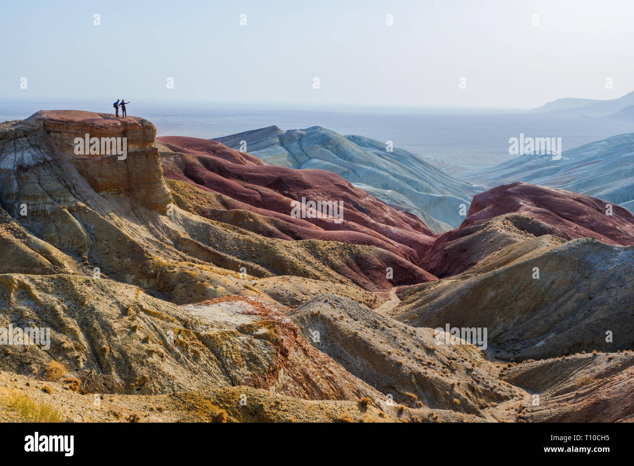 Reisende stehen am Rande einer Klippe vor dem Hintergrund einer epischen Wüste Berg Landschaft.. Nationalpark Altyn-Emel. Kasachstan Stockfoto