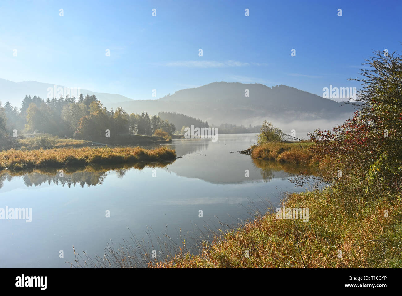 Idyllischer morgen Landschaft an einem See im Herbst. Gruentensee, Allgäu, Bayern, Deutschland. See mit Gras, Büsche, Bäume, Hügel und blauer Himmel Stockfoto