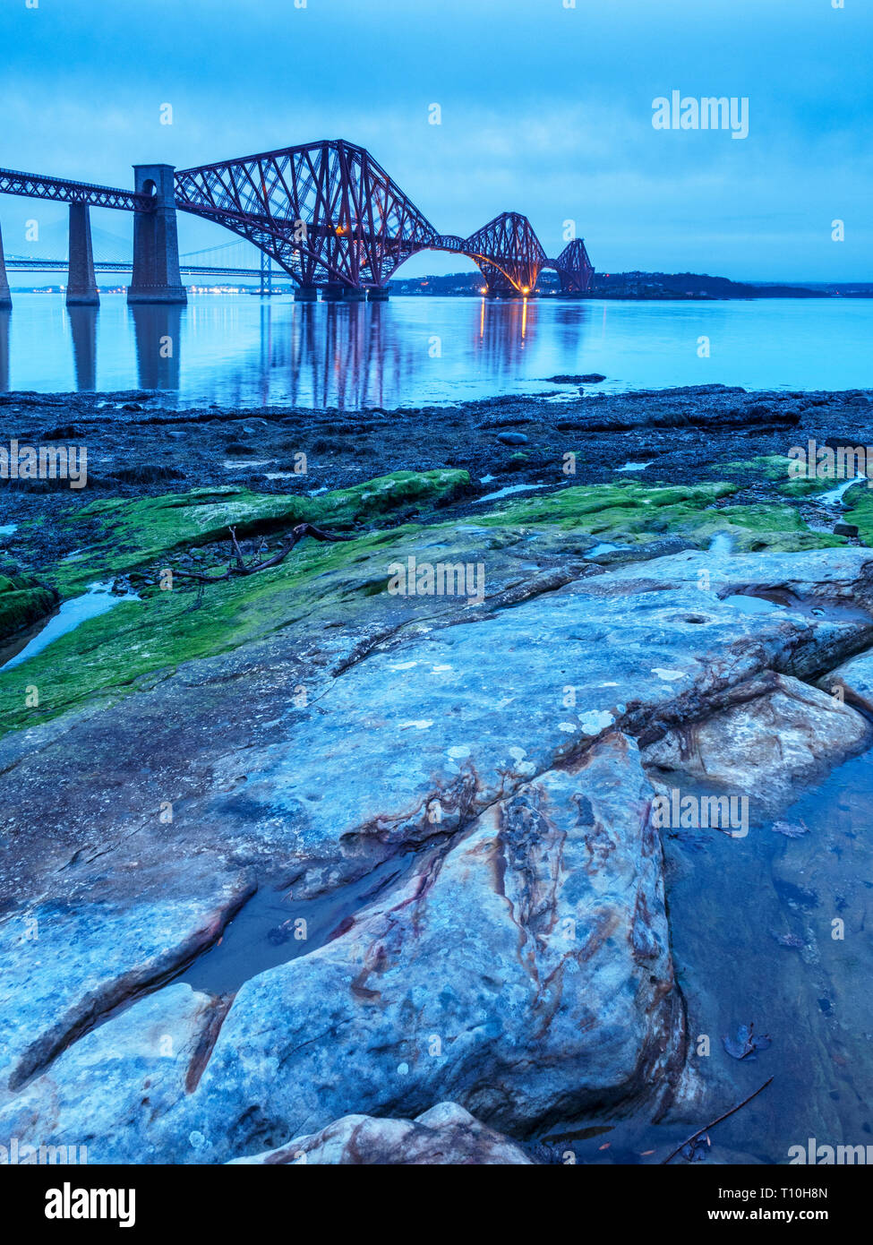 Leuchtet auf auf die Forth Brücke von der felsigen Ufer in South Queensferry Edinburgh Schottland Stockfoto