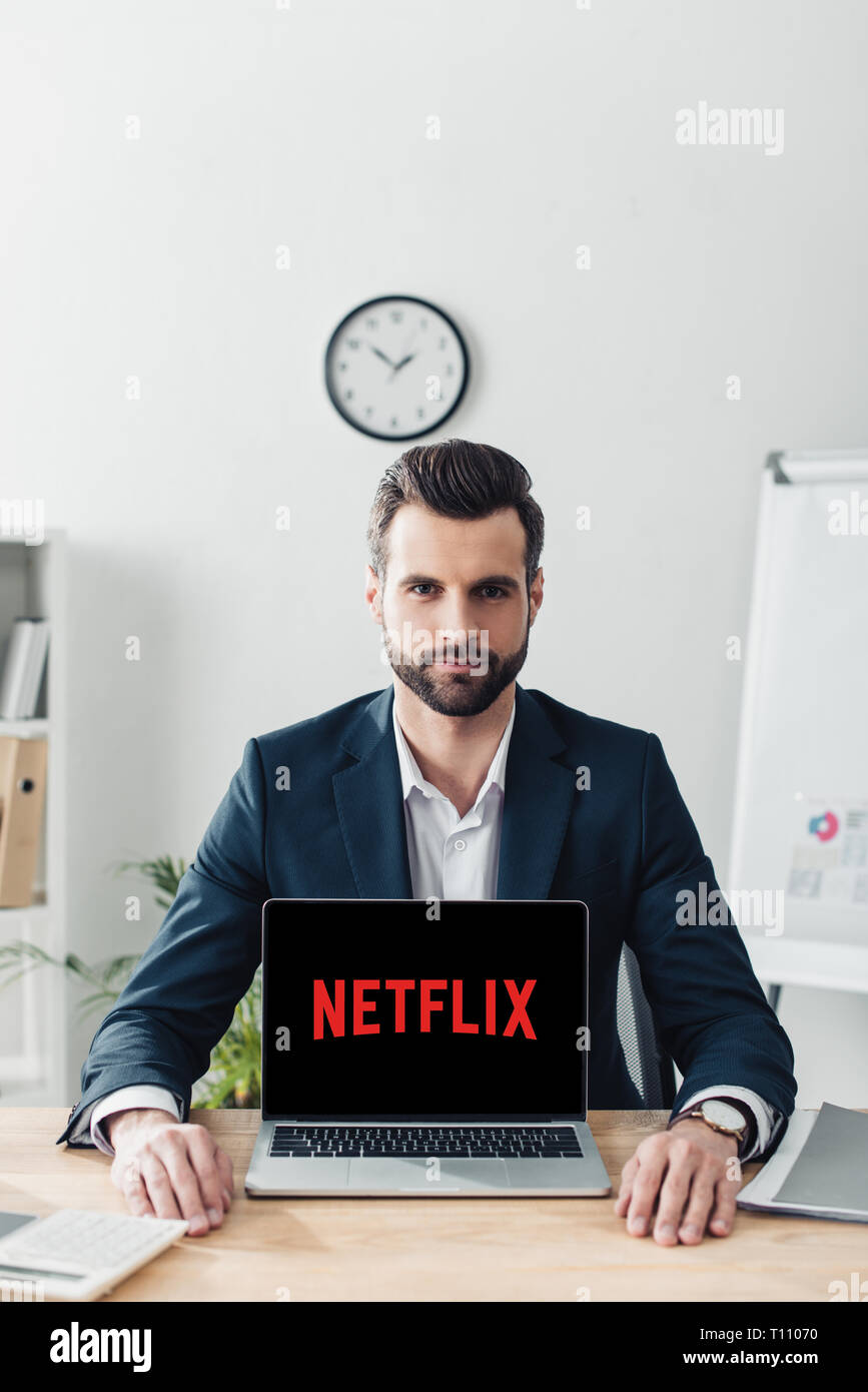 Stattliche Berater im Anzug mit Laptop mit Netflix Webseite auf dem Bildschirm Stockfoto