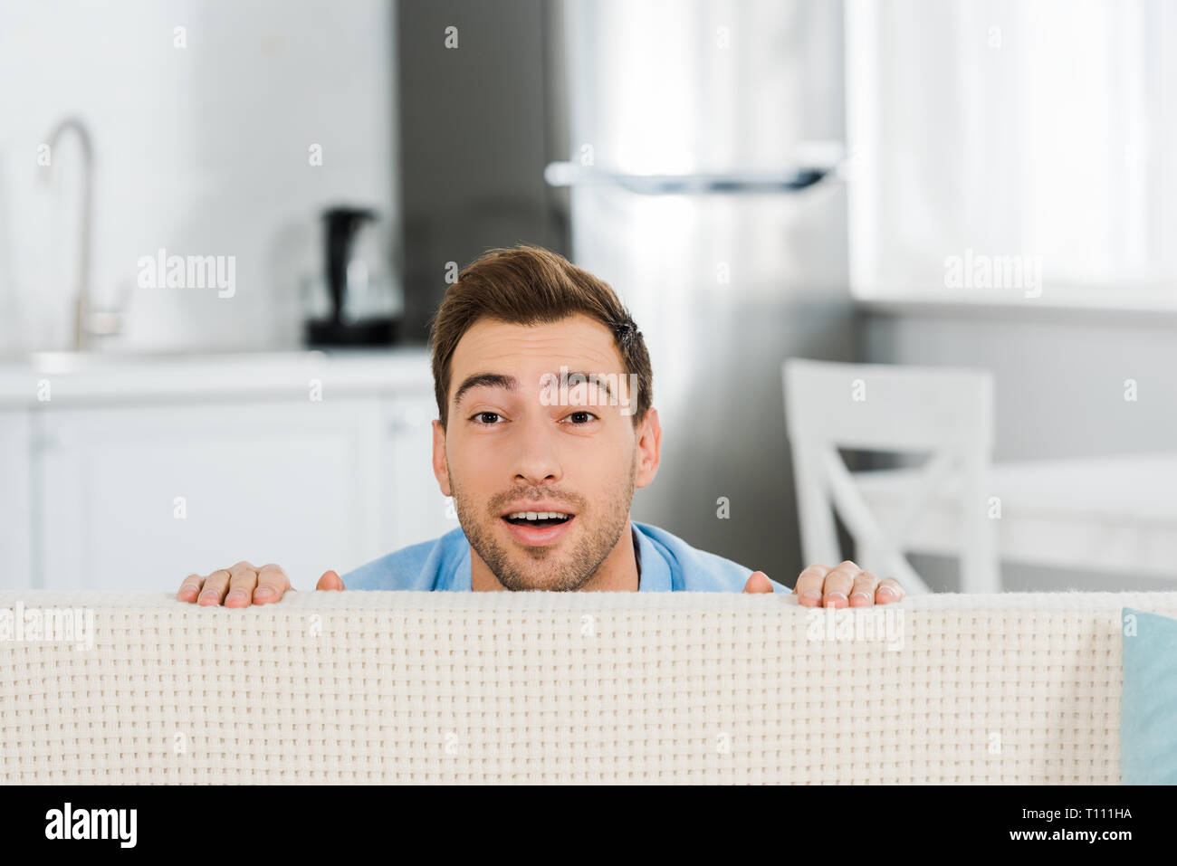 Überrascht, stattlicher Mann mit Kamera suchen und verstecken sich hinter  Couch zu Hause Stockfotografie - Alamy