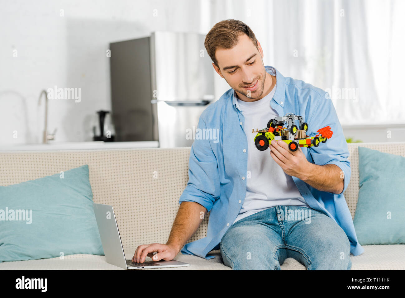 Schöner Mann sitzen auf der Couch und halten Spielzeug Auto zu Hause Stockfoto
