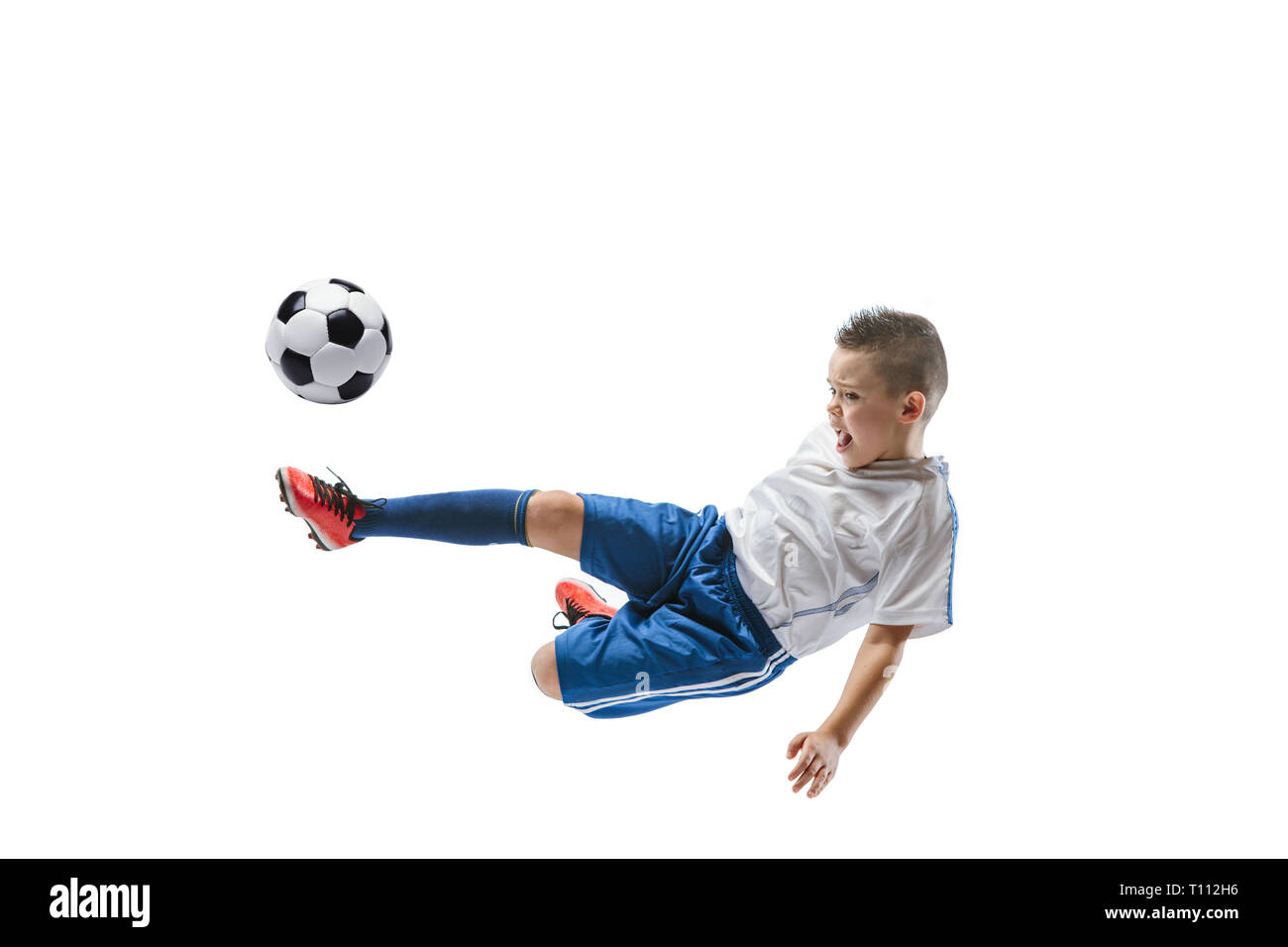 Junge kickt den Ball. Foto auf weißem Hintergrund. Fußball-Spieler in Bewegung im Studio. Fit springen Junge in Action, Jump, Bewegung im Spiel. Stockfoto