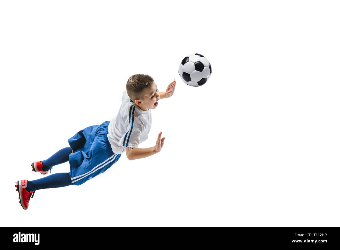 Junge kickt den Ball. Foto auf weißem Hintergrund. Fußball-Spieler in Bewegung im Studio. Fit springen Junge in Action, Jump, Bewegung im Spiel. Stockfoto