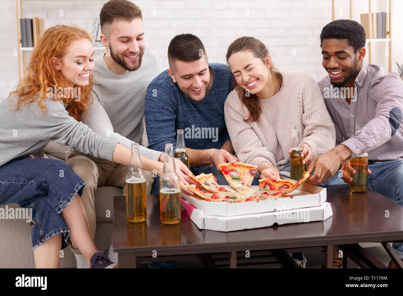 Freunde essen Pizza. Sie Spaß an Home Party Stockfoto