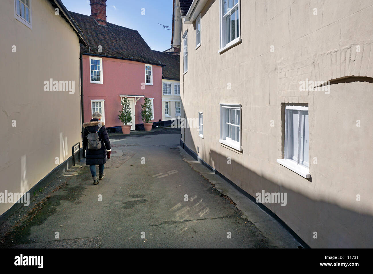 Einsame Frauen walklng durch Rückseite sdtreet Hedinghmam Casle, Essex, England Stockfoto