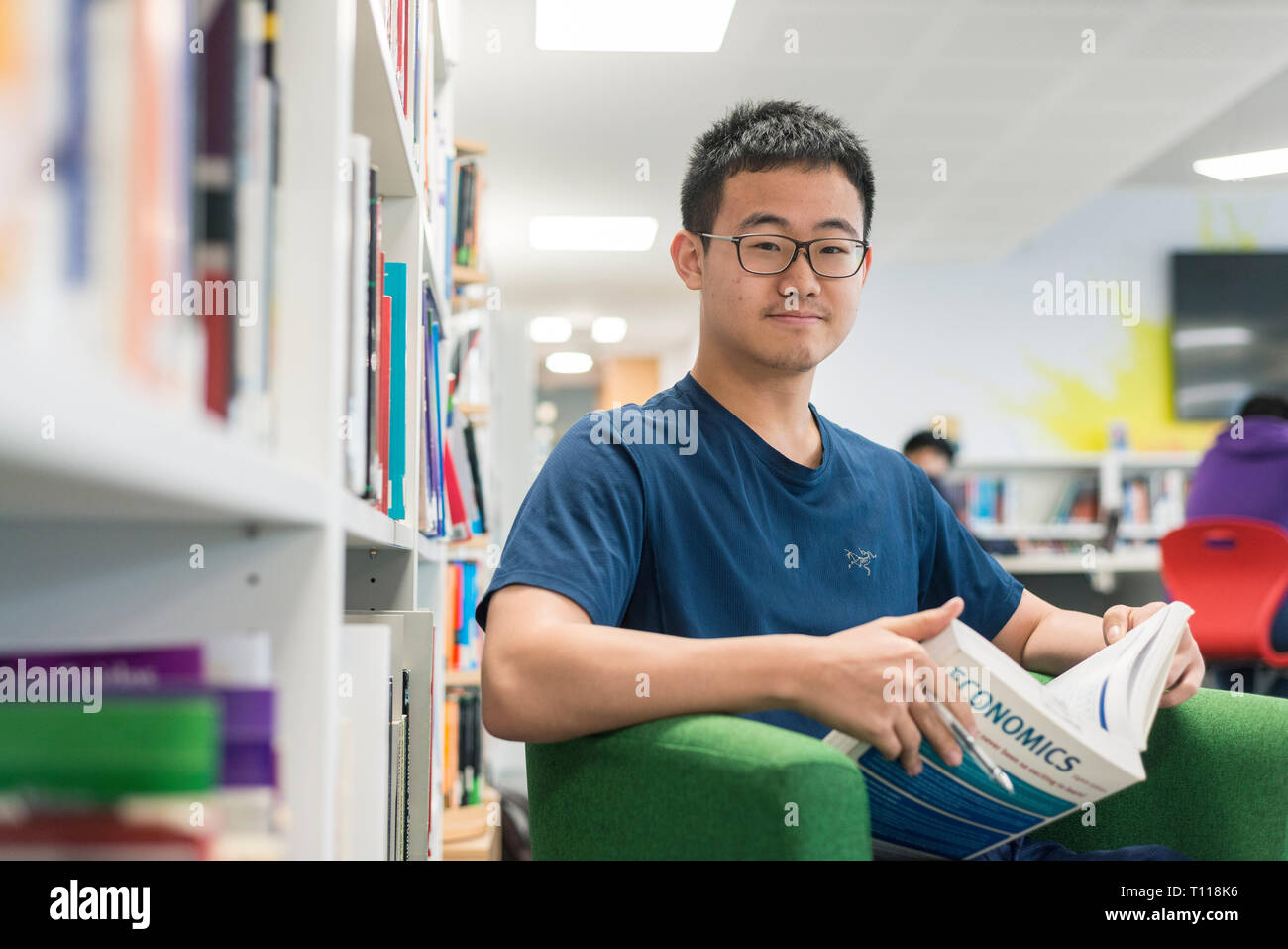 Ein männlicher Südostasiatischen student sitzt und liest in der Bibliothek Stockfoto