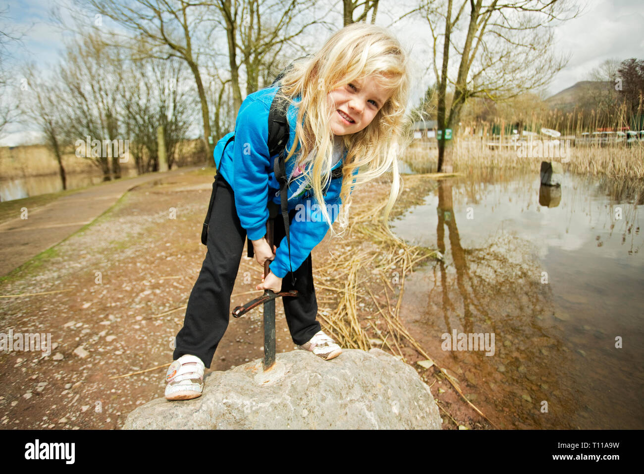 Großbritannien, Wales, Llangorse Lake. Kind versucht, Königin von England zu werden an einem Stein feiert König Artus' Excalibur Schwert in t geworfen Stockfoto