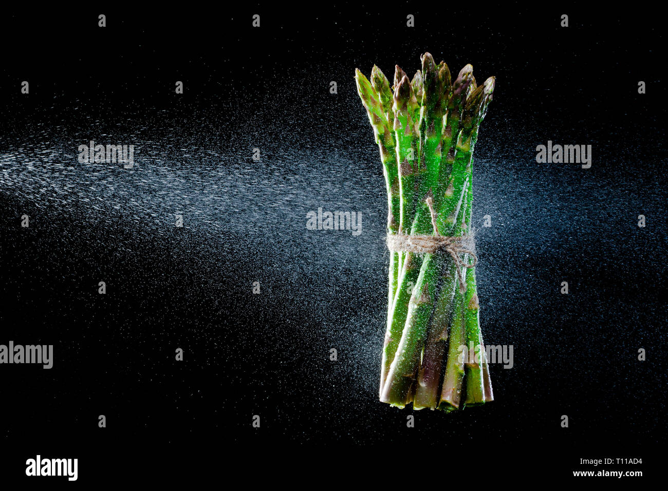 Spargel in Spritzer auf schwarzem Hintergrund. Close-up. Eine Reihe von Obst und Gemüse in Bewegung. Stockfoto