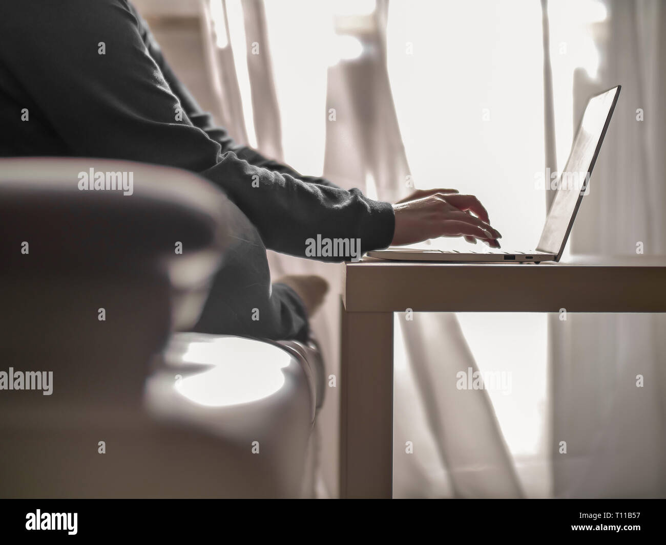 Frau Texteingabe auf einem Laptop beim Sitzen auf einem Sofa Stockfoto