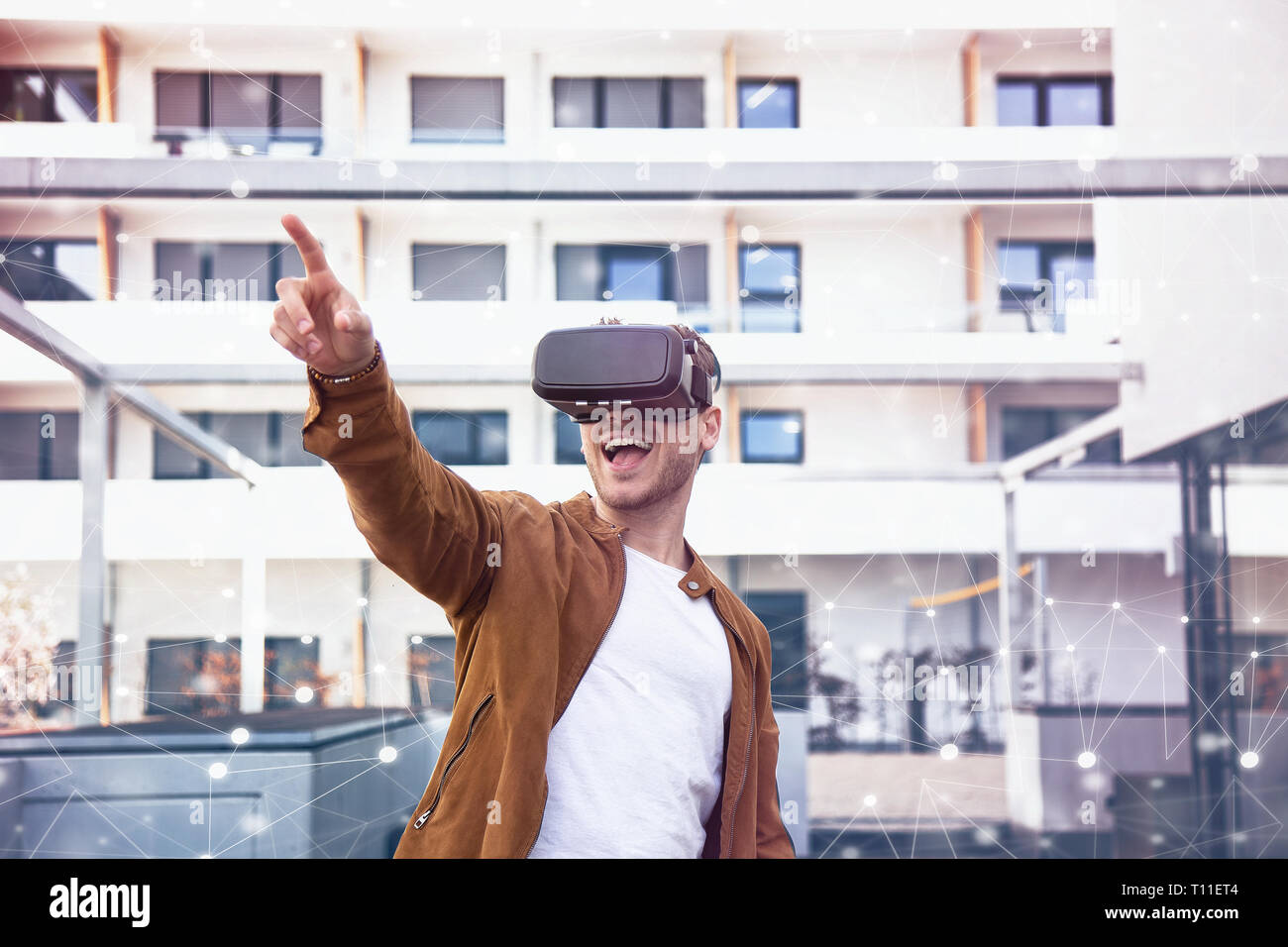 Fröhlich junger Erwachsener charmanter Mann mit VR Virtual Reality Brillen mit Draw Hintergrund Stockfoto
