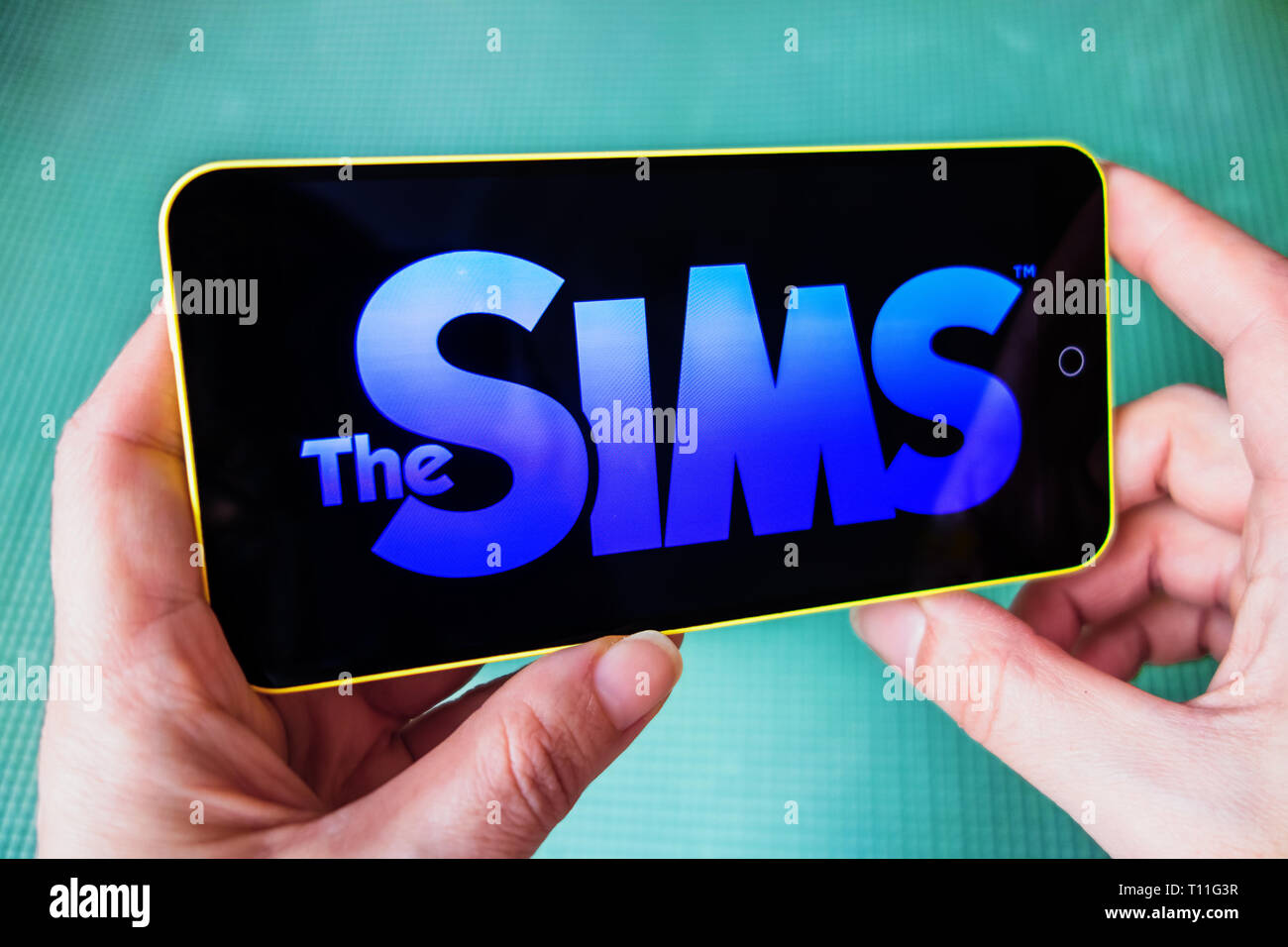 Berdyansk, Ukraine - März 4, 2019 - Nahaufnahme von Hand der Person spielen Die Sims Mobile Game Anmeldung Stockfoto