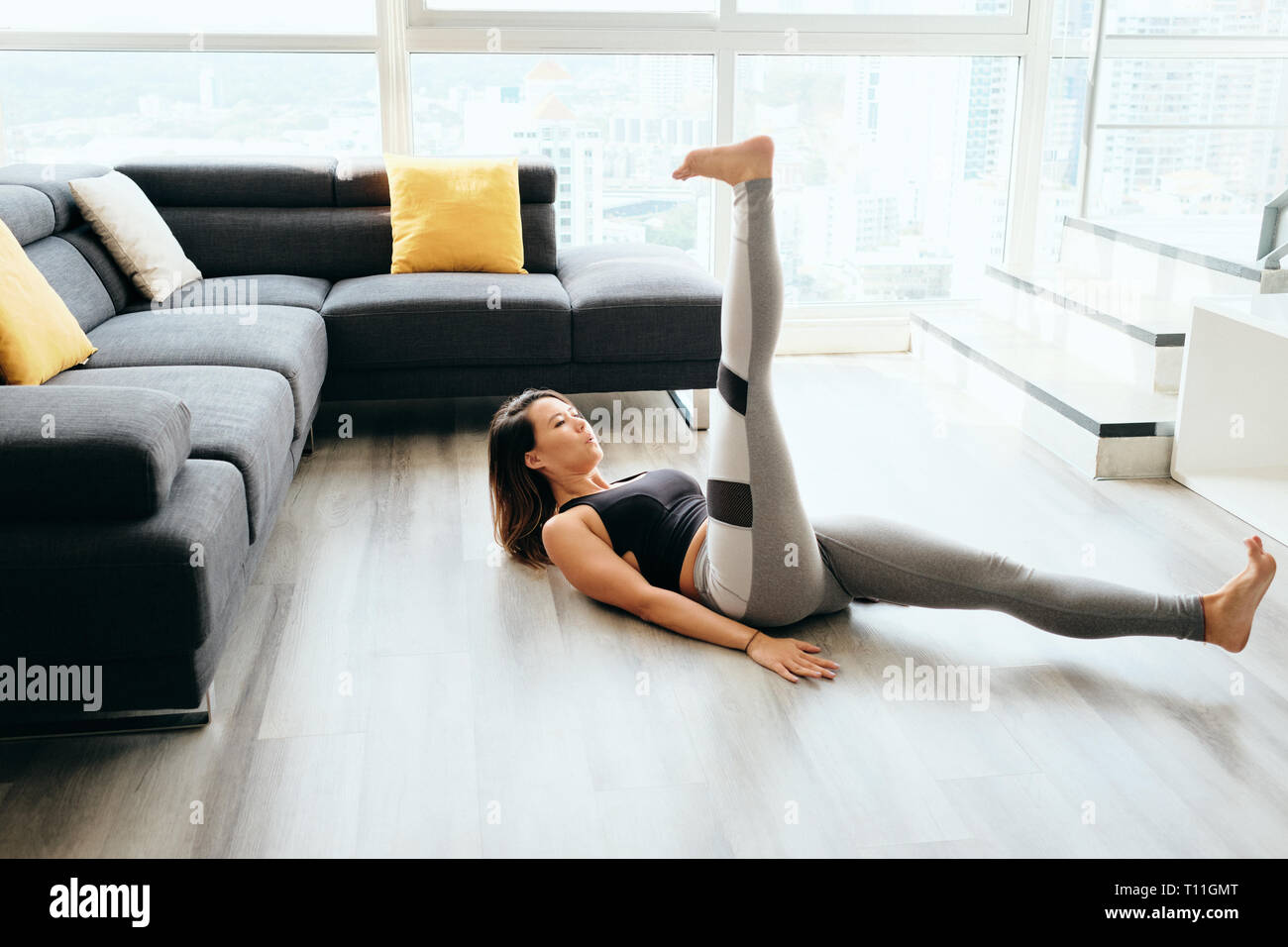 Fit Pacific Islander Frau Training zu Hause. Schönen weiblichen Athleten, die sich für das Wohlergehen der heimischen Fitnessstudio, Training Ihr Bauch. Sie legt Stockfoto