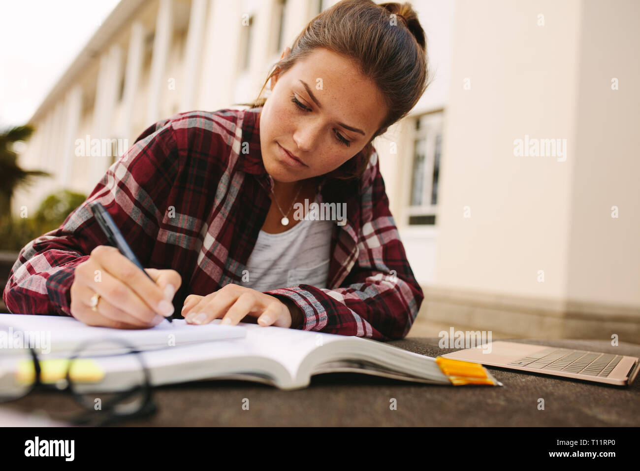 Studentin am College Campus sitzen und sich Notizen. Mädchen Studenten studieren an der Universität. Stockfoto