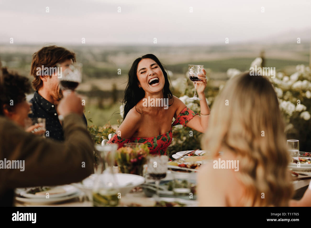 Lächelnde Frau heben Wein Glas und die Unterhaltung mit Freunden zum Abendessen. Gruppe von Menschen, die großartige Zeit im Dinner Party. Stockfoto