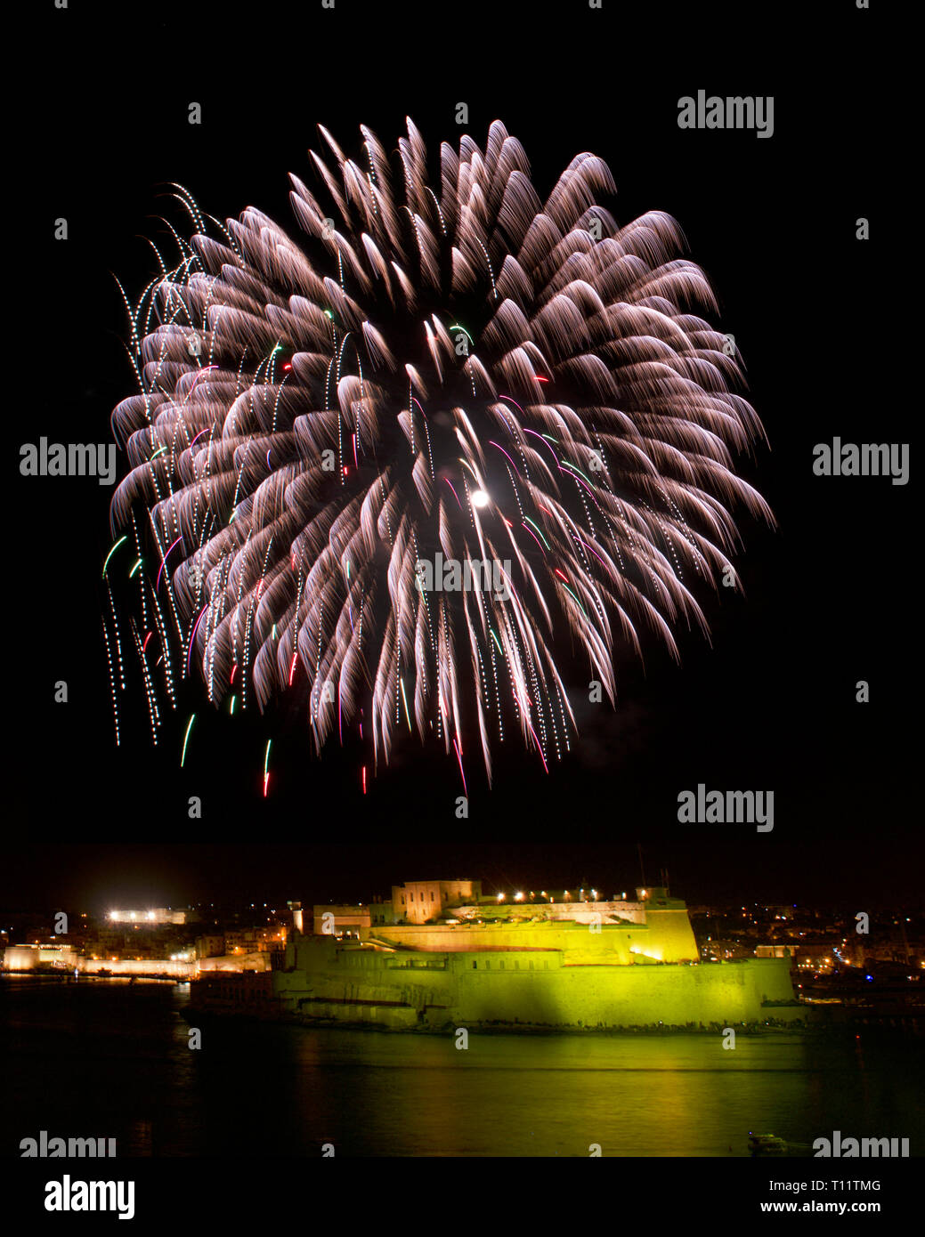 Feuerwerk, bunten Feuerwerk am schwarzen Himmel Hintergrund, Fireworks Explosion in den dunklen Himmel mit Stadt silouthe auf der Unterseite, Feuerwerk auf Malta Stockfoto
