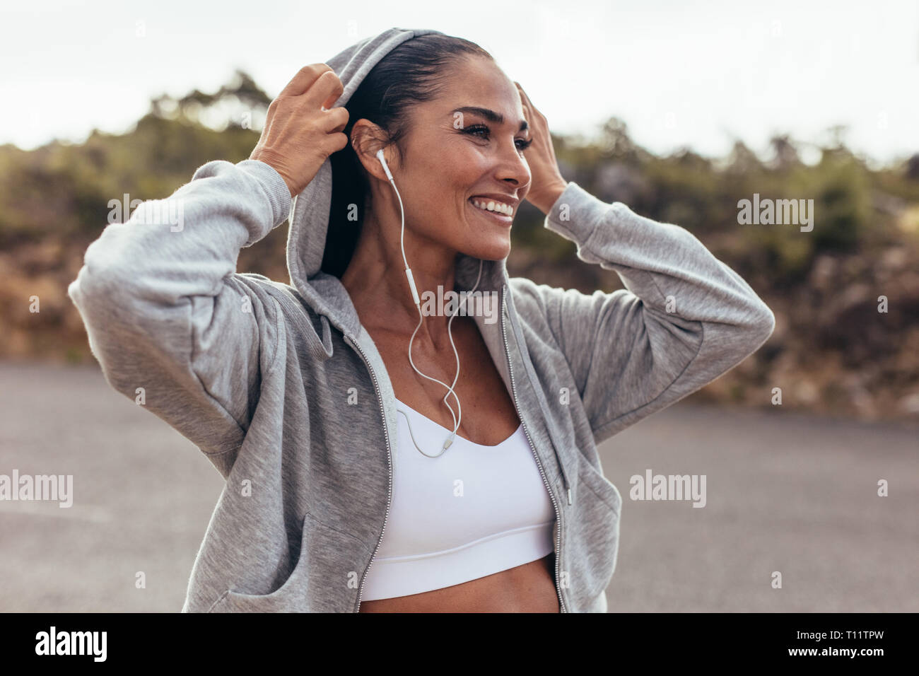 Fitness Frau trägt ein T-Shirt zu Fuß im Freien. Lächelnd weibliche auf Spaziergang am frühen Morgen. Stockfoto