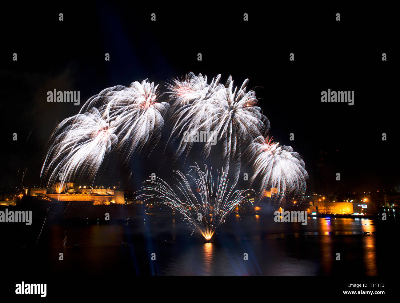 Feuerwerk, bunten Feuerwerk am schwarzen Himmel Hintergrund, Fireworks Explosion in den dunklen Himmel mit Stadt silouthe auf der Unterseite, Feuerwerk auf Malta Stockfoto