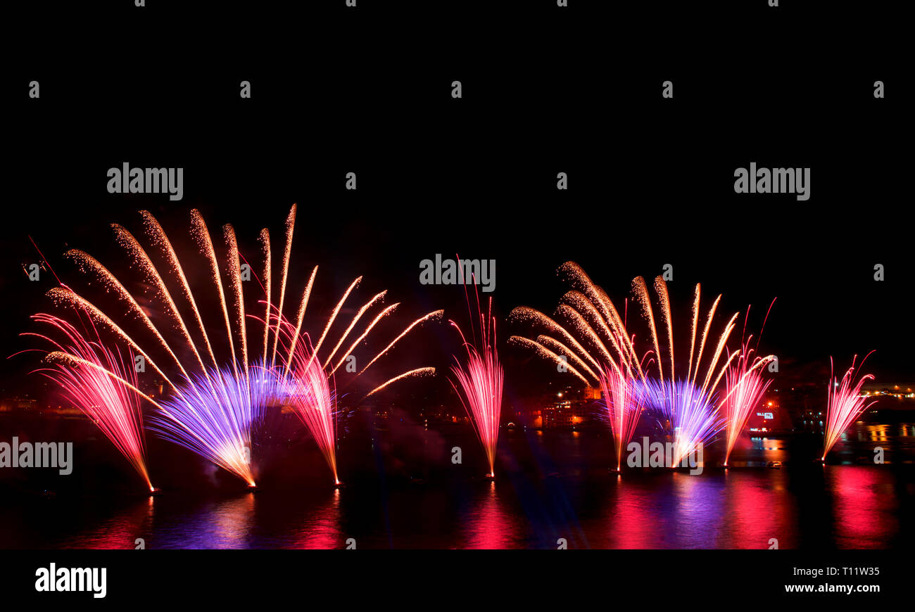 Feuerwerk, bunten Feuerwerk am schwarzen Himmel Hintergrund, Fireworks Explosion in den dunklen Himmel mit Stadt silouthe auf der Unterseite, Feuerwerk auf Malta Stockfoto