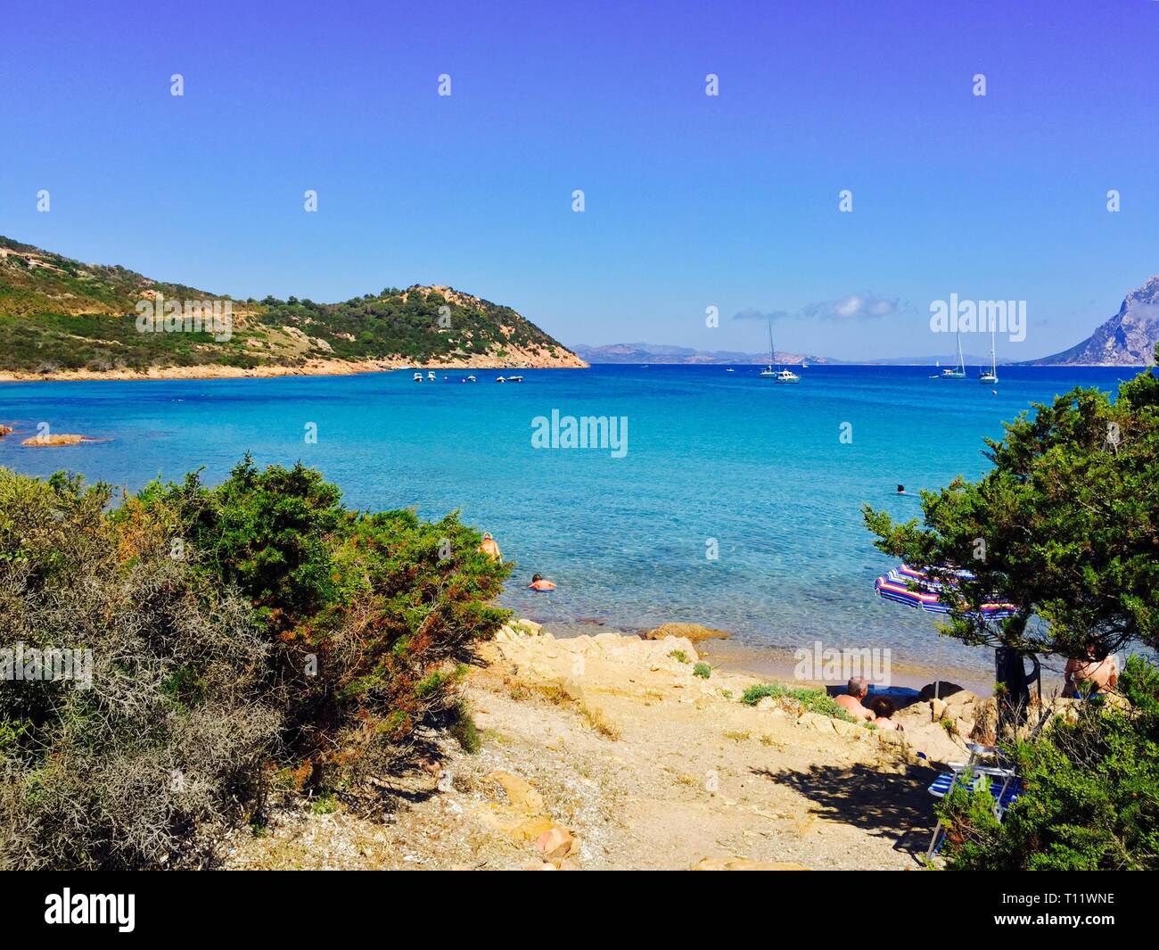 Eine schöne Aussicht auf den Strand in Sardinien mit Blick auf weitere Berge und Inseln und das hellblaue Wasser Stockfoto