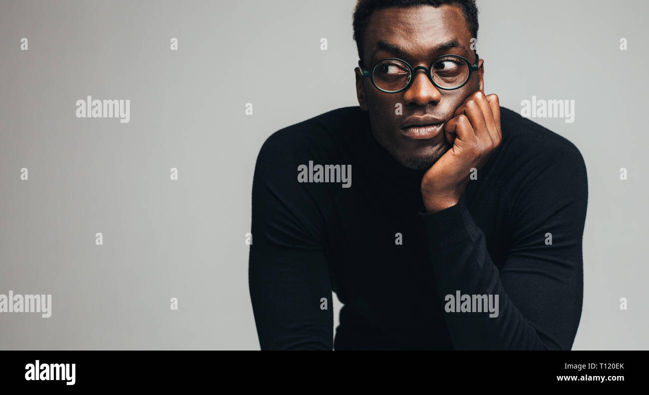 Afrikanischer Mann mit Brille weg schauen gegen grauen Hintergrund. Männliches Modell in Schwarz t-shirt bei copy Raum starrte. Stockfoto