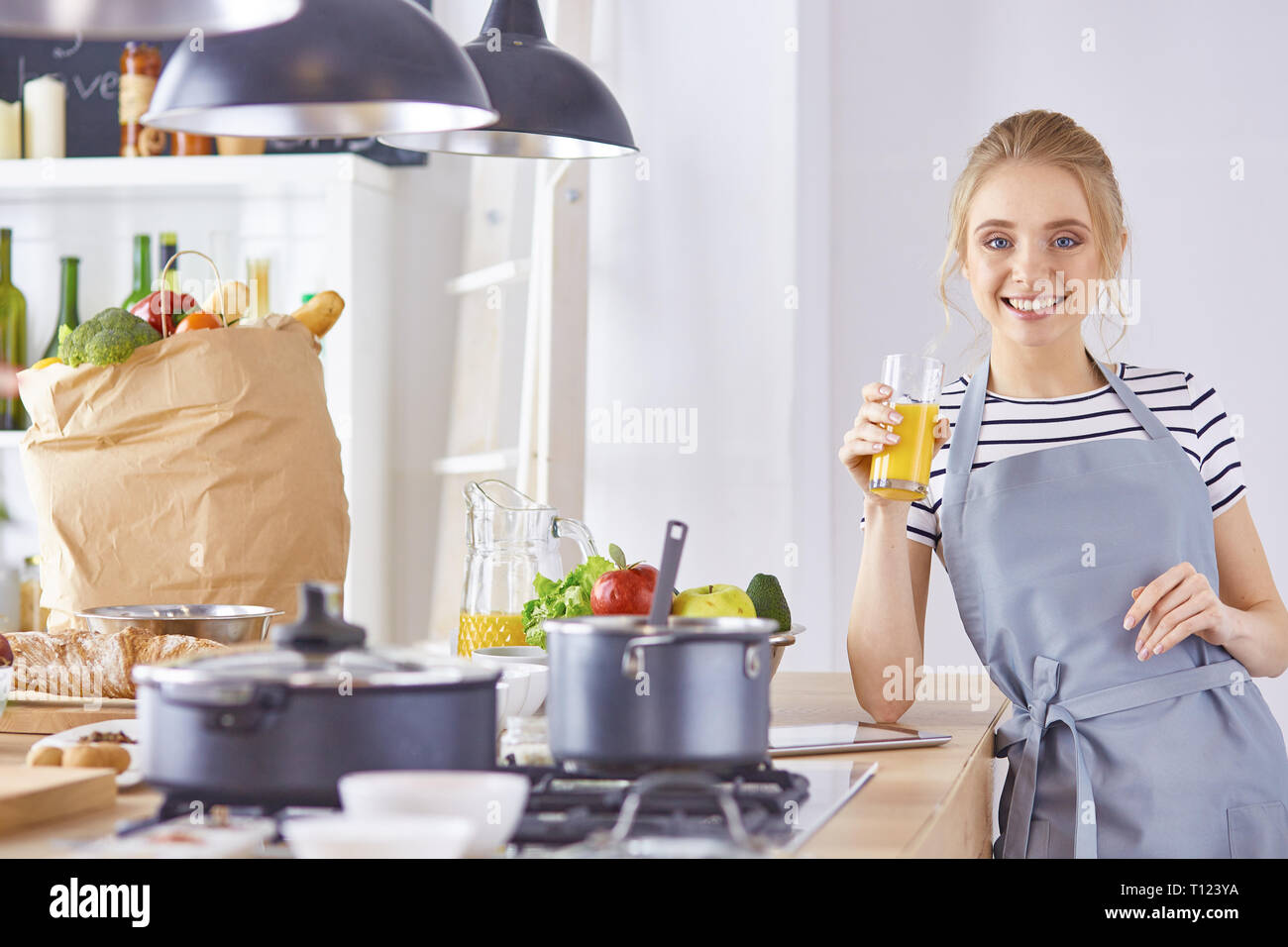 Das Mädchen am Tisch in der Küche mit einem Glas orange Jui Stockfoto