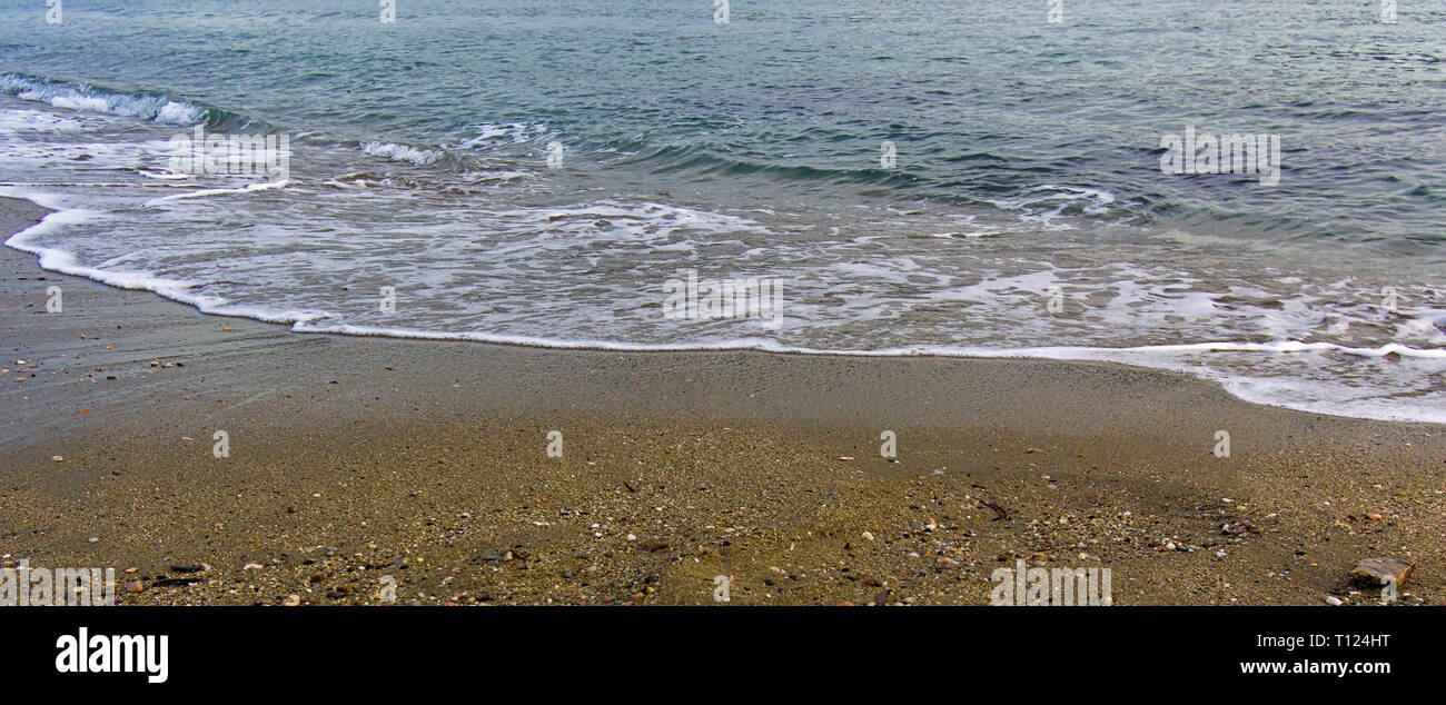 Sea Wave erreichen Sandstrand. Bunte Wasser und Sand. Schöne Küste detail, panorama bild. Stockfoto