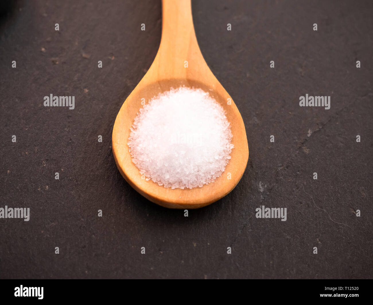 Löffel aus Holz mit marine Salz auf einer Schiefertafel Platte Stockfoto