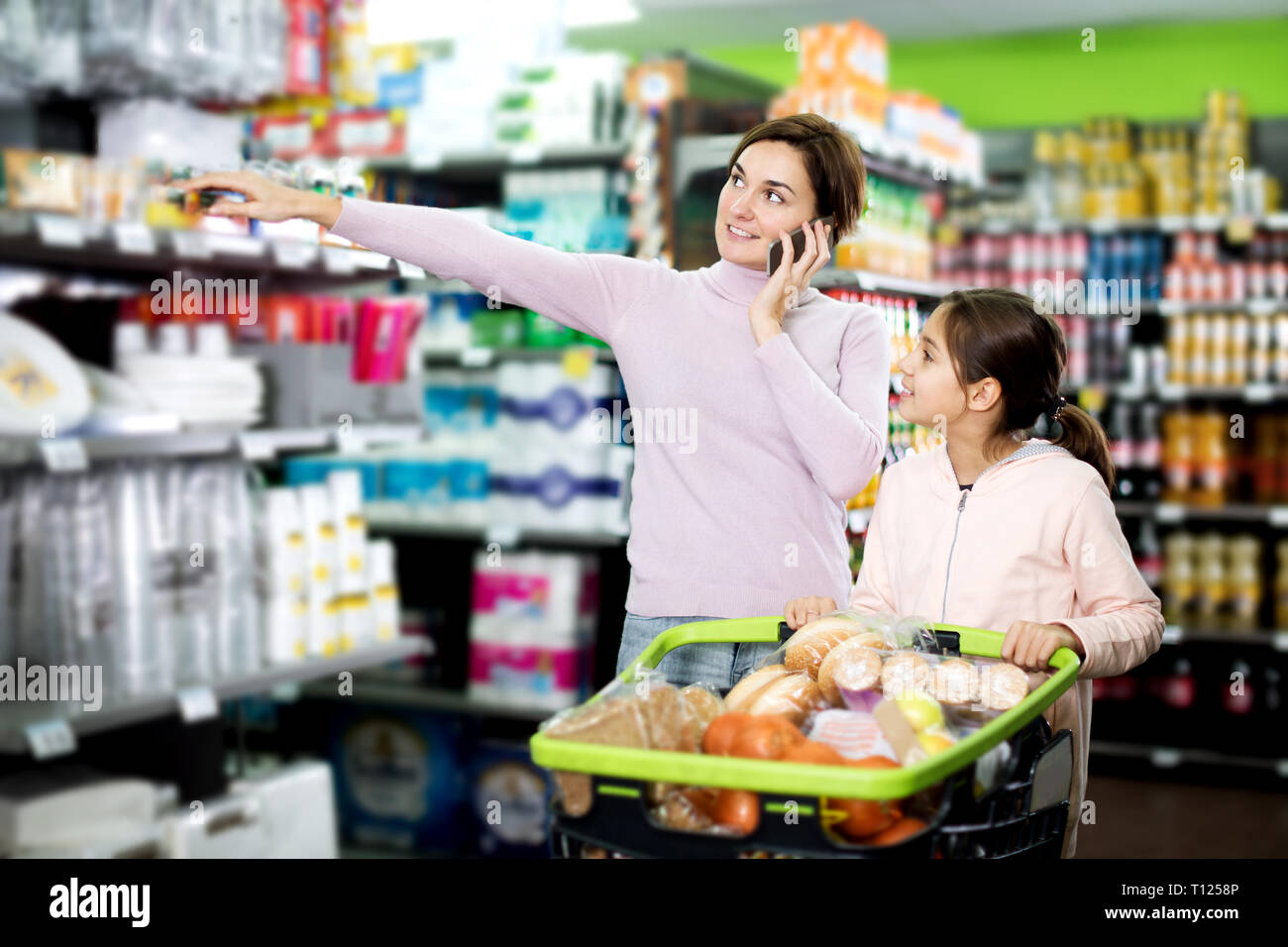 Glückliche junge Frau Kunde mit Mädchen telefonieren über das Einkaufen im Supermarkt zu konsultieren Stockfoto