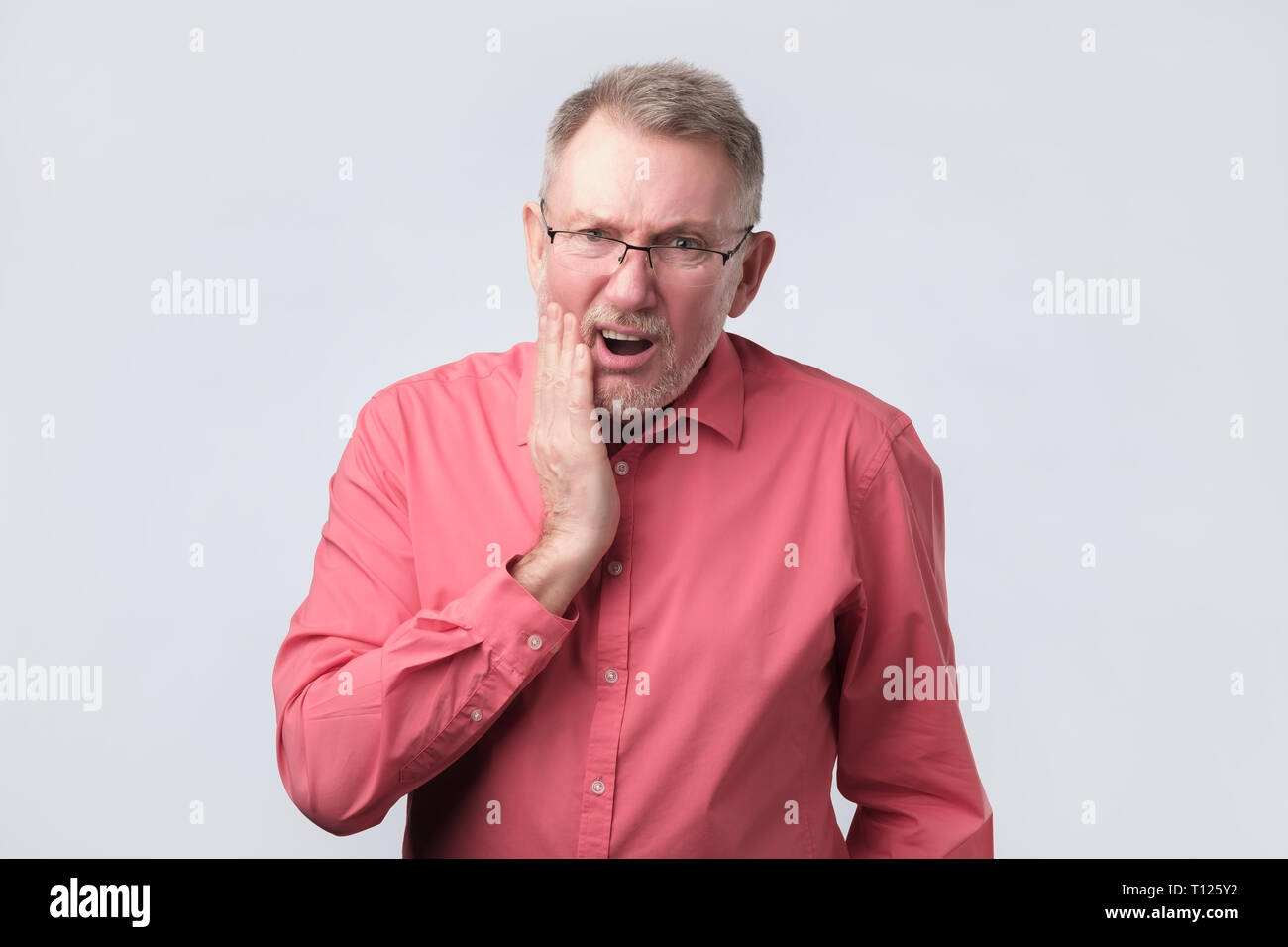 Älterer Mann im roten T-Shirt Zahn Schmerzen leiden. Er muss zum Arzt. Stockfoto