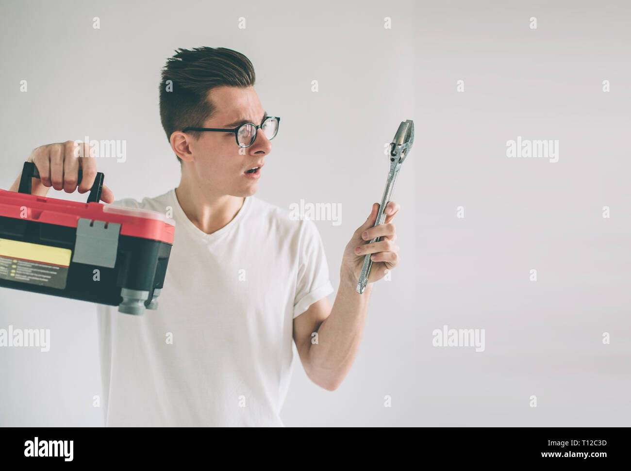 Lustige portrait umgekippt Handwerker. Nerd eine Brille trägt. Nicht weiß, wie die Werkzeuge für die Reparatur zu verwenden. Stockfoto