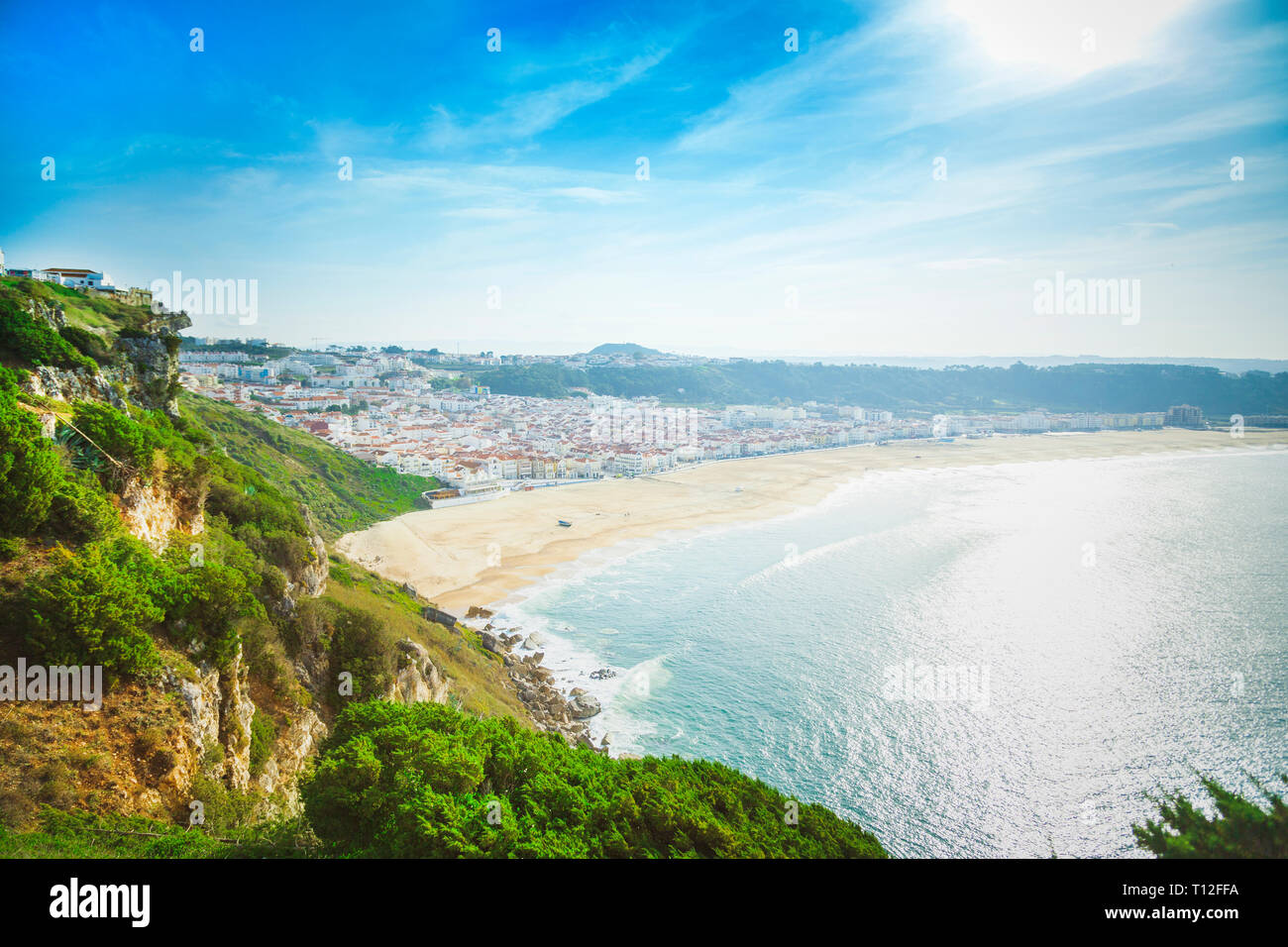 Riesiger Sandstrand mit großen Wellen in sonniger Tag. Surfer vor Ort. Nazare, Portugal Stockfoto