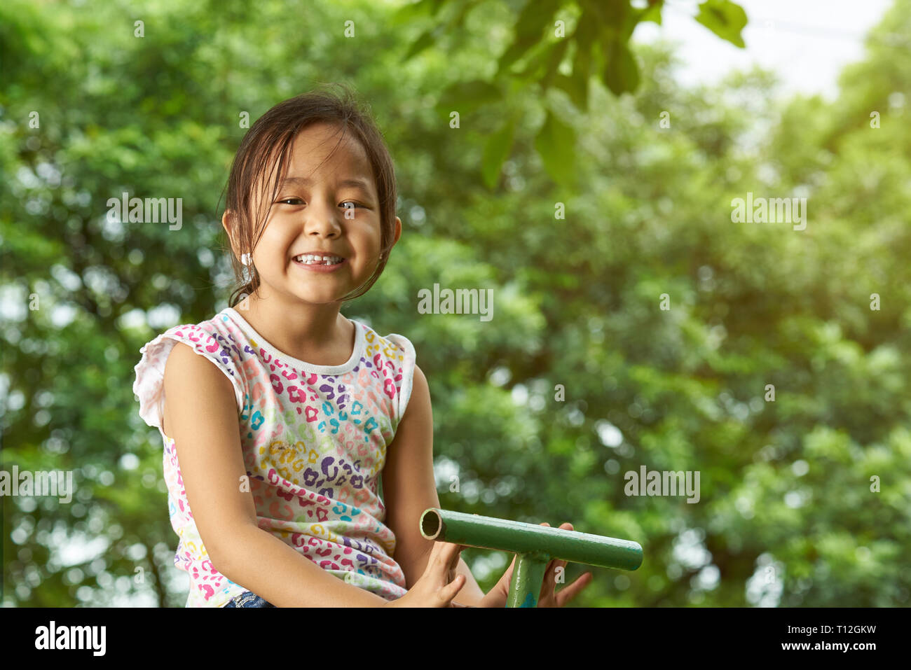 Cute asian kleine Mädchen lächelnd auf die natürlichen sonnigen Hintergrund Stockfoto