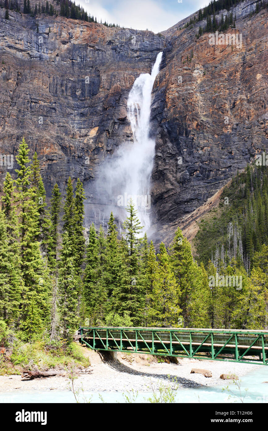 Fußgängerbrücke über Kicking Horse River zu den mächtigen Takakkaw Falls in den Yoho Nationalpark in der Nähe von Feld, British Columbia, Kanada. Der Gletscher - FBI-Wasser Stockfoto