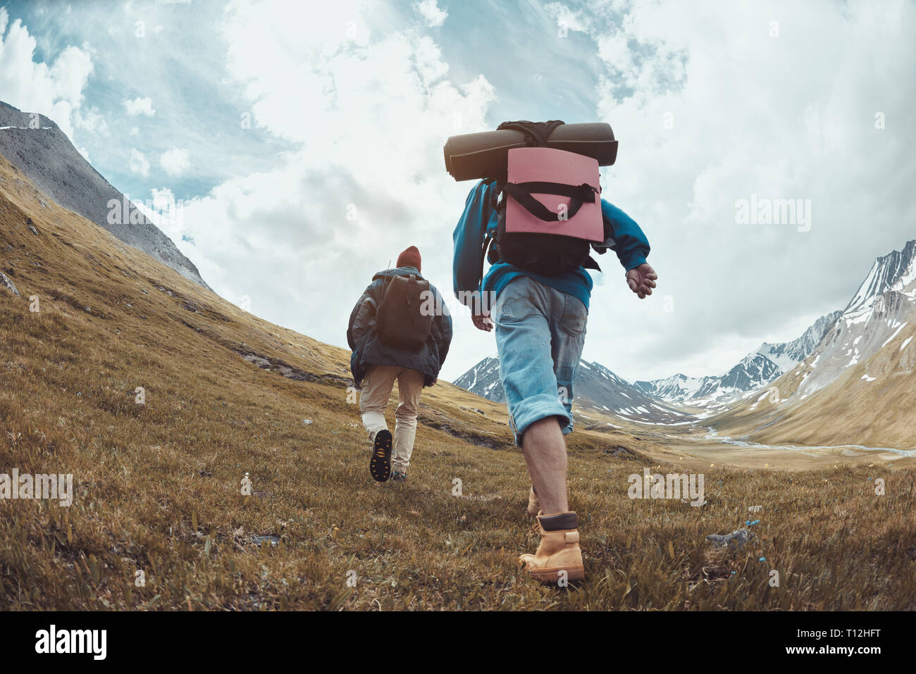 Zwei Wanderer in legere Kleidung und Rucksäcke geht bergauf in den Bergen Stockfoto