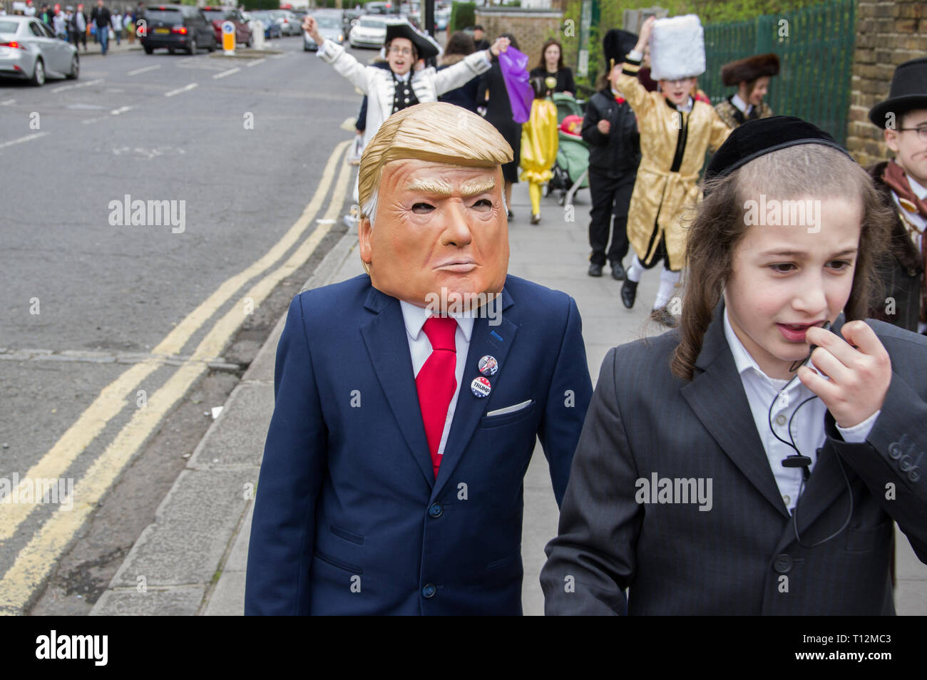 Junge Marching in Donald Trump Maske und Anzug Jacke für den Jüdischen Feiertag Purim in Stamford Hill, London, 21. März 2019, Stockfoto