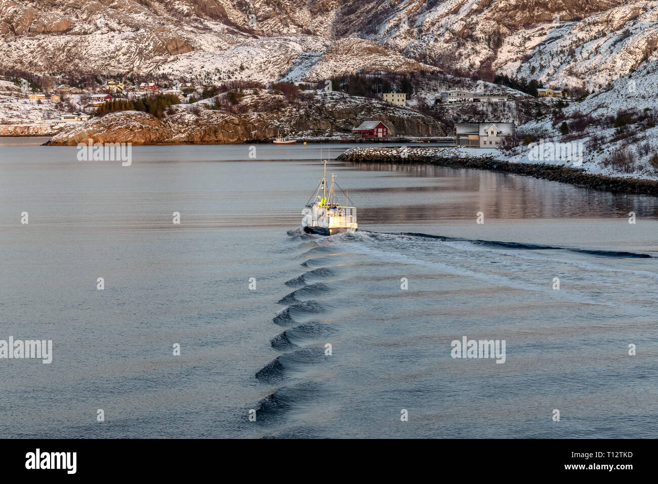 Ein kleines, einsames Fischerboot, nähert sich der heimathafen der Stadt in den norwegischen Fjorden. Stockfoto
