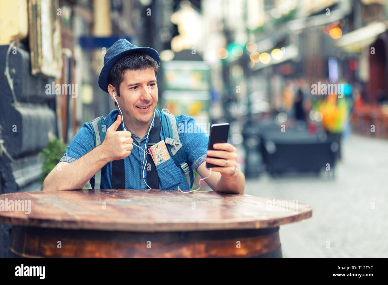 Reisende mit trendigen Look in einer Videokonferenz mit Daumen hoch, während die Erkundung Straßen der großen Städte - Junger Mann genießen City vibes Stockfoto