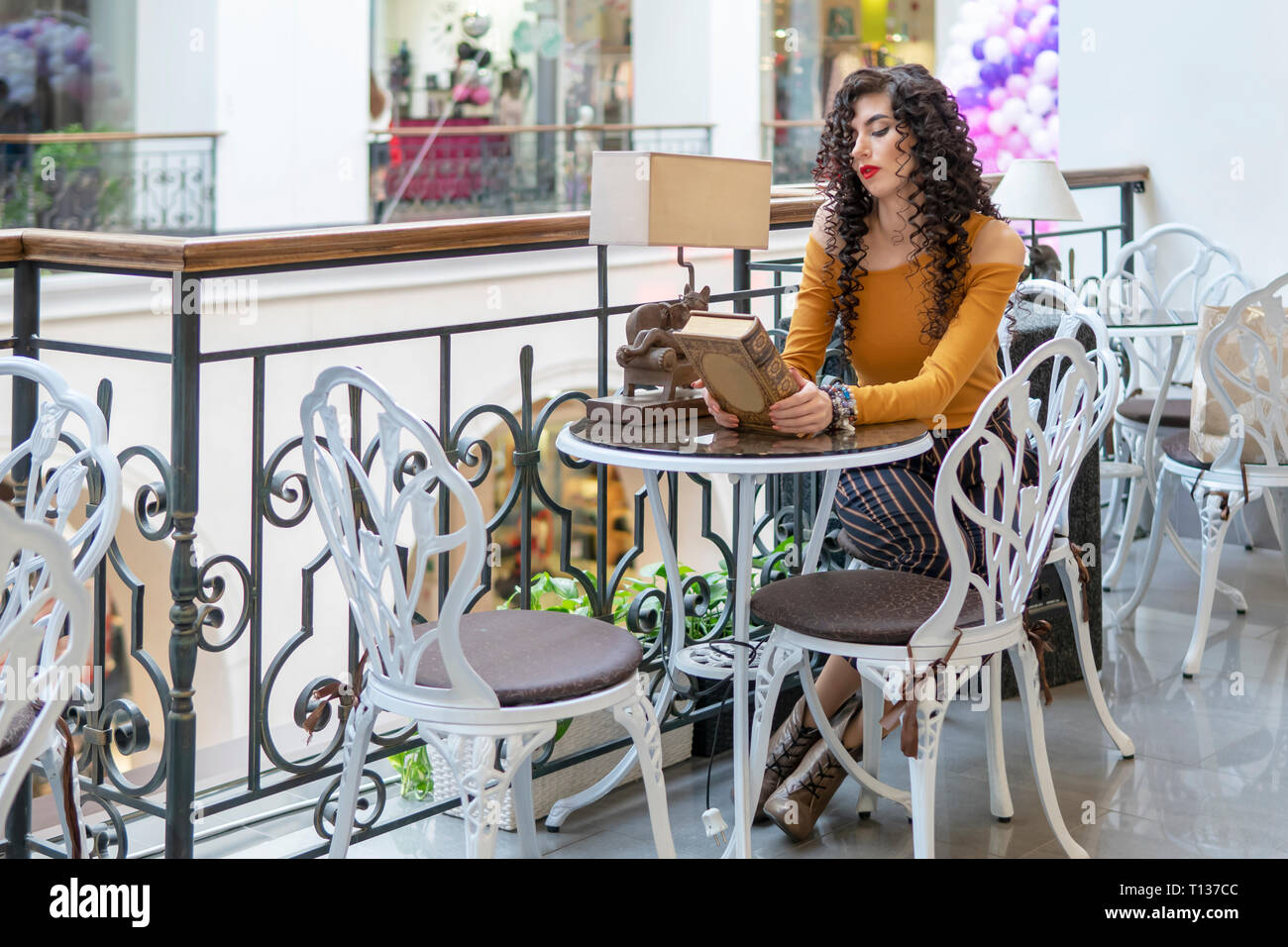 Schön lockig-Leitung Frau mit ein geschlossenes Buch an einem Tisch in einem Cafe Stockfoto