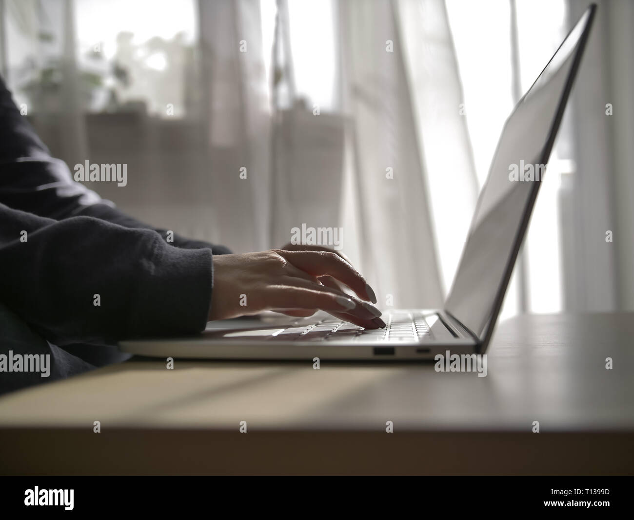 Weibliche Hände Schreiben auf der Tastatur des Laptops auf den Hintergrund des Fensters Stockfoto