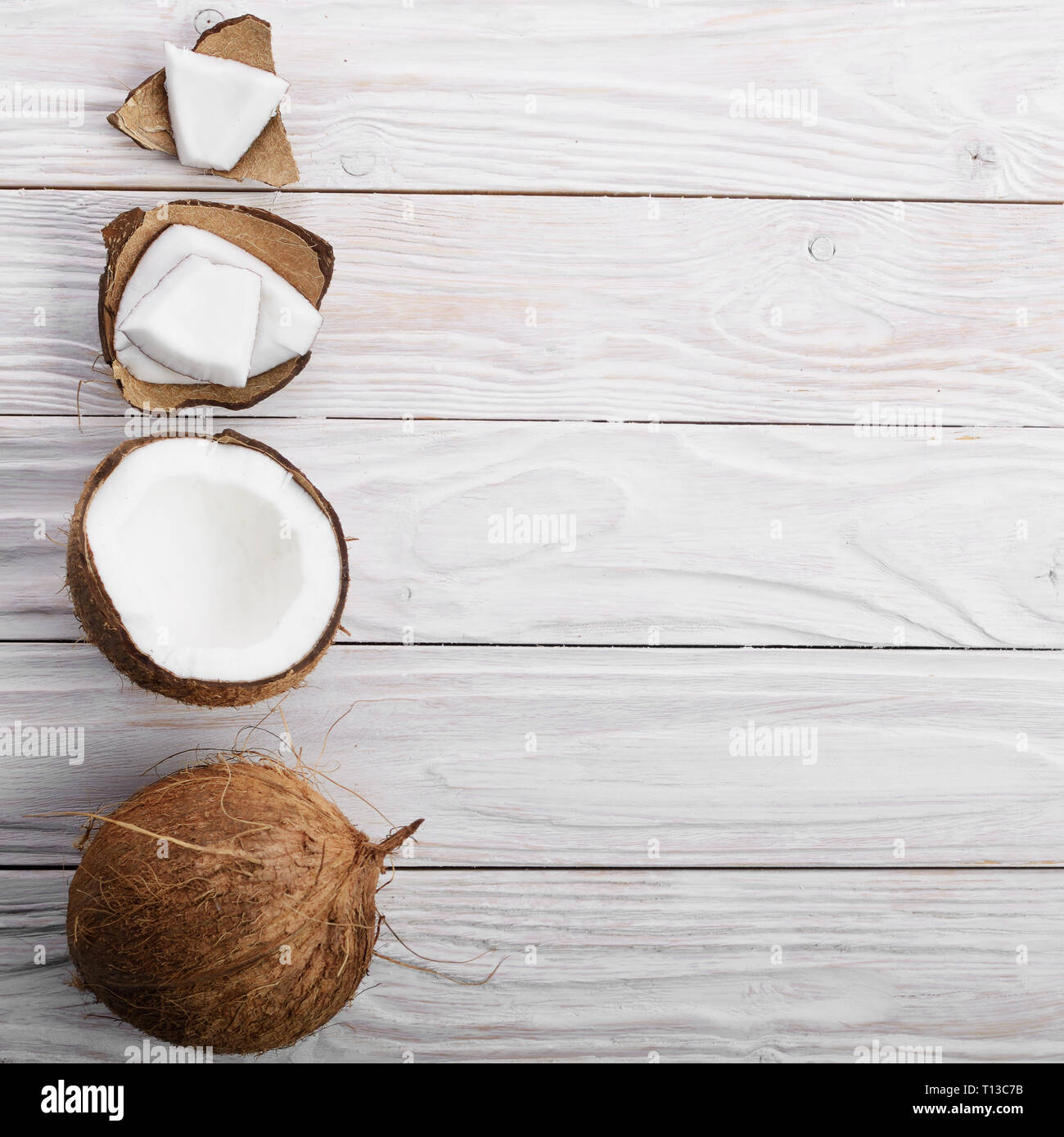 Flach Hintergrund der Kokosnuss, Kokosnussschalen und Fleischstücke auf weissem Holztisch Stockfoto