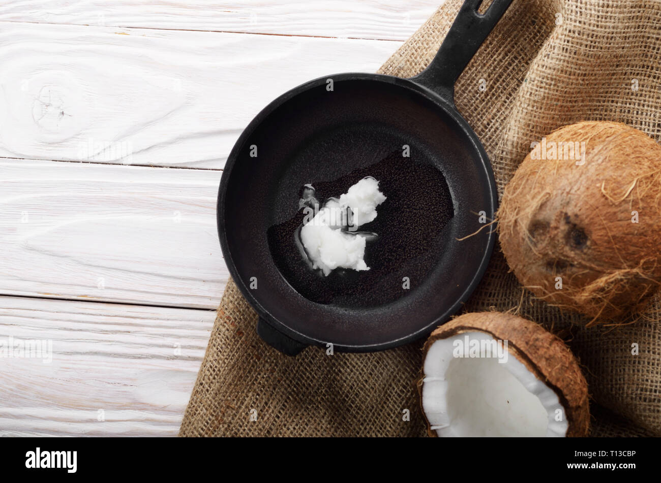 Kokosnuss, Shell mit Fleisch, Gusseisen Skillet auf Hanf Sack auf weißen Küche aus Holz Tisch Stockfoto