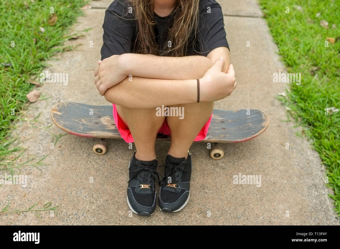 Nicht wiederzuerkennen, junges Mädchen sitzt auf einem Skateboard. Stockfoto
