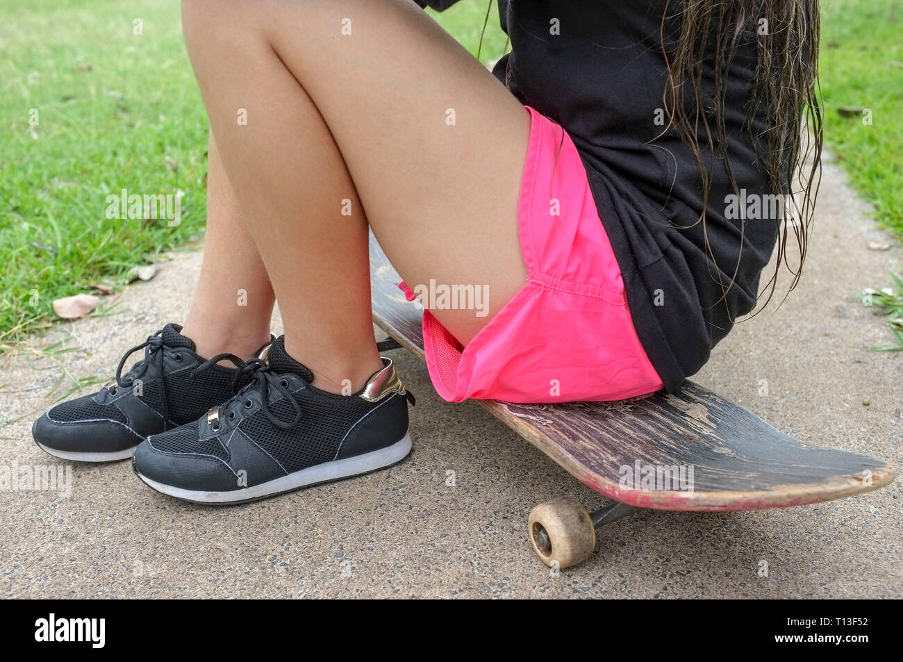 Nicht wiederzuerkennen, junges Mädchen sitzt auf einem Skateboard. Stockfoto