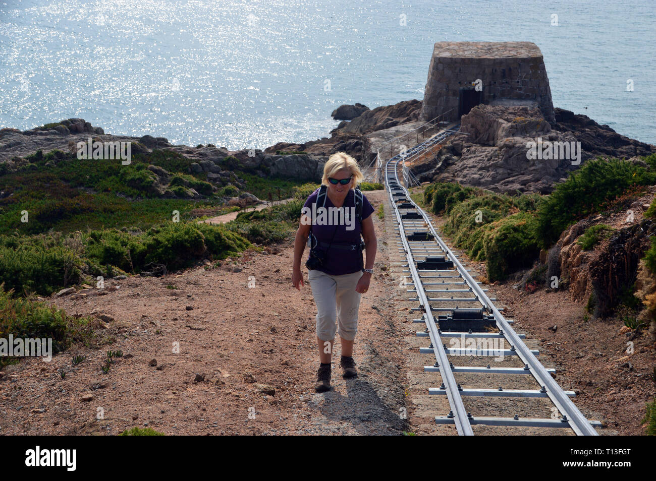 Frau Wanderer zu Fuß durch die Schmalspurbahn, die zu den Wert Haus Teil der La Rosière Entsalzungsanlage auf der Insel Jersey, Stockfoto