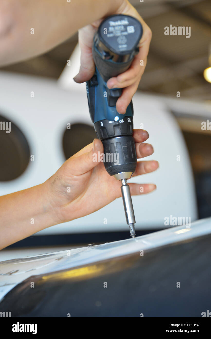 Ein Porträt, in einer aeronautical engineers Hände mit einer Bohrmaschine. Ein Flugzeuge Windows sind im Hintergrund sichtbar. Stockfoto